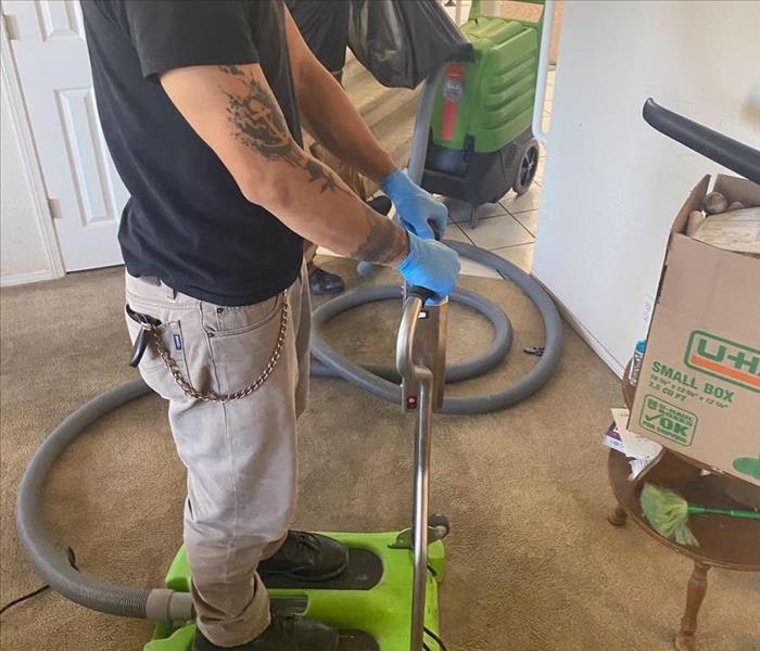 Male SERVPRO employee using SERVPRO equiptment to clean up standing water